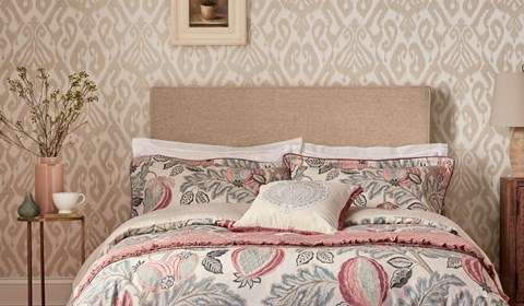 Neutral tone wallpaper with pastel pink bedding in bedroom